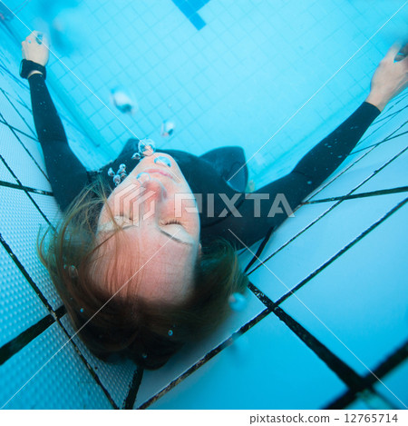 Female diver with eyes closed underwater in swimming pool Female diver with eyes closed underwater in swimming pool 12765714