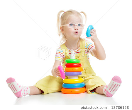 Funny kid in eyeglases playing colorful pyramid toy isolated 12786138