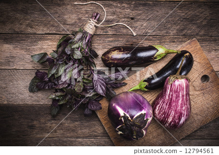 Aubergines and basil on chopping board in rustic style Aubergines and basil on chopping board in rustic style 12794561