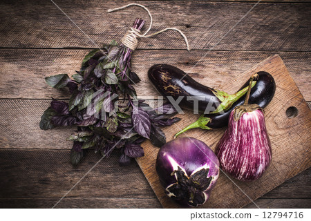 rustic style aubergines and basil on chopping boa