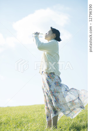 A woman drinking water on the meadow A woman drinking water on the meadow 12796390