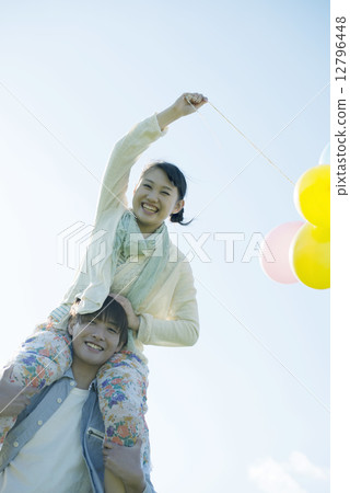 A couple holding a balloon and doing a shoulder car 12796448