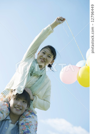 A couple holding a balloon and doing a shoulder car 12796449