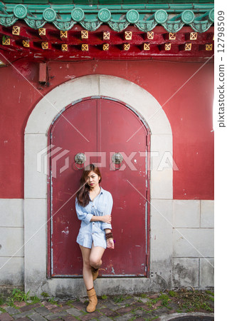 Asian woman standing by red Chinese door 12798509