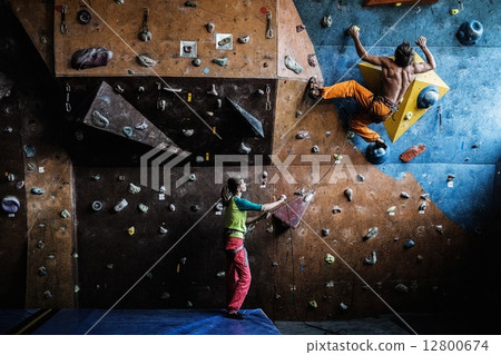 Muscular man practicing rock-climbing on a rock wall indoors 12800674