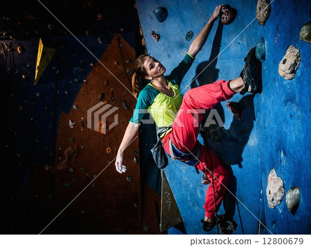 Young woman practicing rock-climbing on a rock wall indoors 12800679