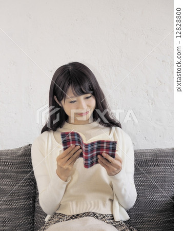 A woman reading a book on a sofa 12828800