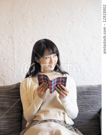 A woman reading a book on a sofa A woman reading a book on a sofa 12828802