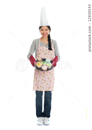 Young Asian girl baking bread and cupcakes, wearing apron and gl Young Asian girl baking bread and cupcakes, wearing apron and gl 12830543
