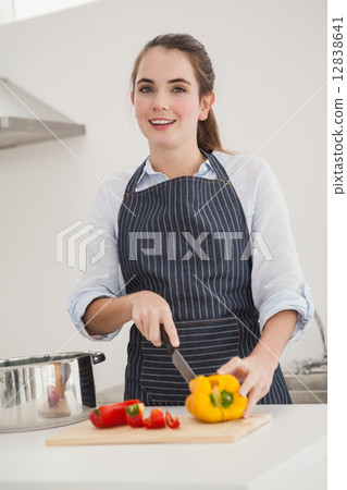 Pretty brunette slicing vegetables at the counter Pretty brunette slicing vegetables at the counter 12838641