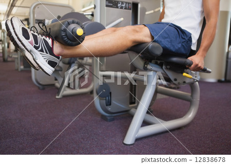 Fit man using weights machine for legs 12838678