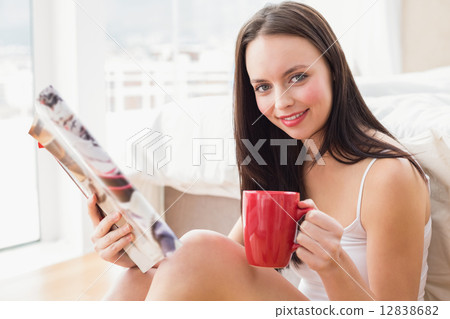 Pretty brunette sitting on floor reading magazine Pretty brunette sitting on floor reading magazine 12838682