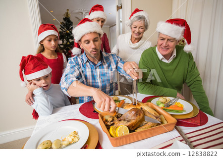 Father in santa hat carving chicken during dinner 12838822