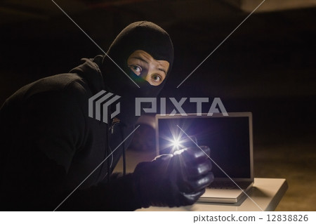 Robber looking at camera while making light with his phone Robber looking at camera while making light with his phone 12838826