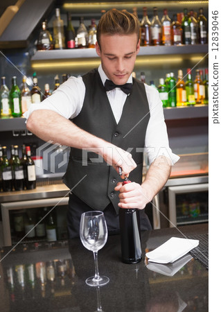 Handsome waiter opening a bottle of red wine Handsome waiter opening a bottle of red wine 12839046