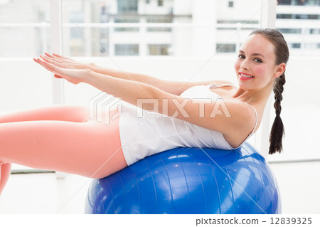 Fit brunette stretching on an exercise ball Fit brunette stretching on an exercise ball 12839325