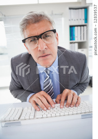 Focused businessman typing at his desk 12839537