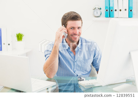 Smiling businessman on the phone at desk 12839551