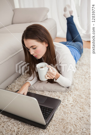 Pretty brunette using laptop on the floor 12839774