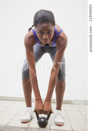 Fit woman lifting up kettlebell 12840005