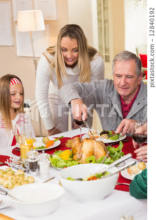 Grandfather carving chicken during christmas dinner 12840192