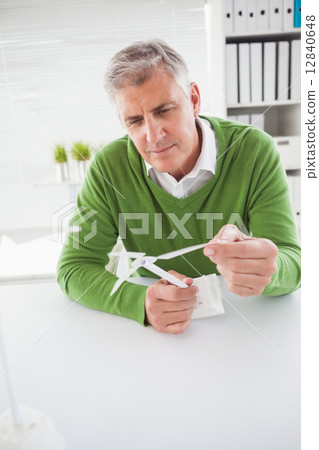 Casual businessman looking at model wind turbines Casual businessman looking at model wind turbines 12840648