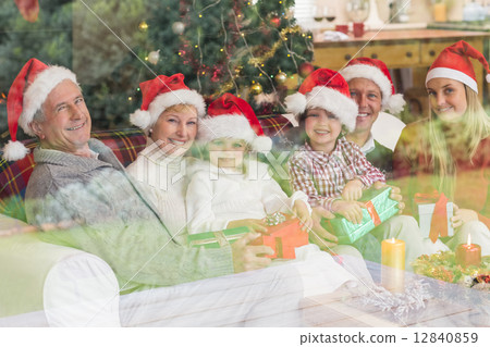 Three generation family opening christmas gifts on couch 12840859