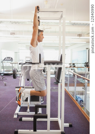 Fit man doing pull ups in fitness studio 12840990