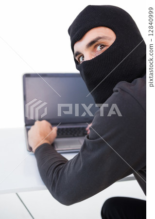 Burglar hacking into laptop while looking at camera Burglar hacking into laptop while looking at camera 12840999