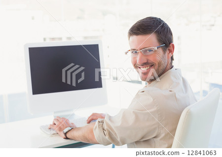 Smiling casual businessman at his desk 12841063