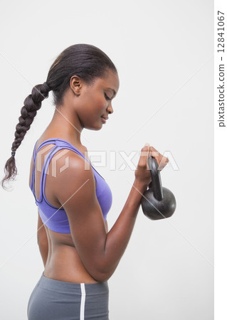 Fit woman lifting up kettlebell 12841067