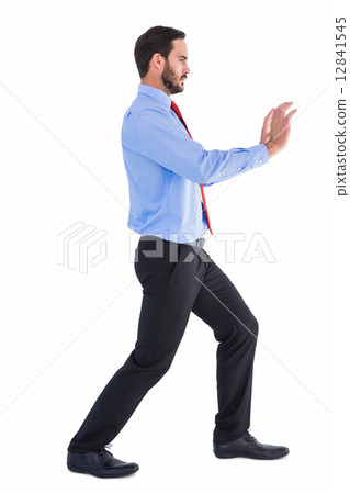 Focused businessman standing and pushing with hands Focused businessman standing and pushing with hands 12841545