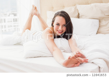 Pretty brunette smiling at camera in bed Pretty brunette smiling at camera in bed 12841653