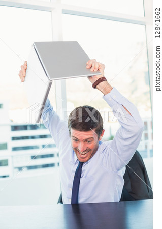 Angry businessman throwing his laptop Angry businessman throwing his laptop 12841662