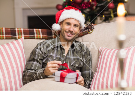 Happy man in santa hat opening a gift Happy man in santa hat opening a gift 12842183
