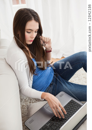 Pretty brunette using laptop on the floor 12842186