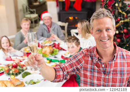 Smiling father toasting at camera in front of his family 12842189