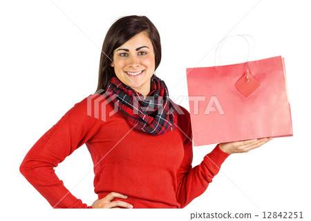 Smiling brunette showing red gift bag 12842251