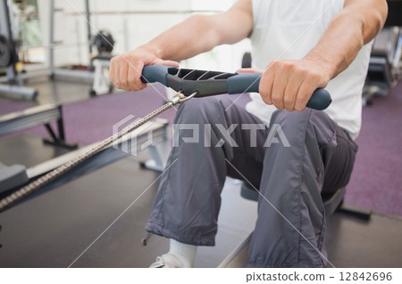 Fit man working out on rowing machine 12842696