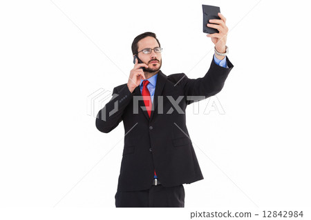 Businessman holding calculator while talking on phone 12842984