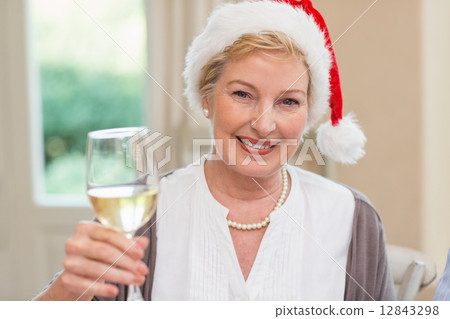 Smiling mature woman in santa hat toasting with white wine Smiling mature woman in santa hat toasting with white wine 12843298