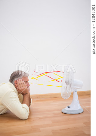 Man lying on floor looking at fan Man lying on floor looking at fan 12843301