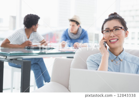 Young creative woman using laptop on couch 12843338