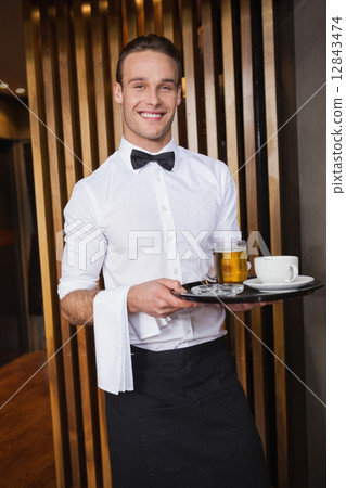 Smiling waiter holding tray with coffee cup and pint of beer 12843474