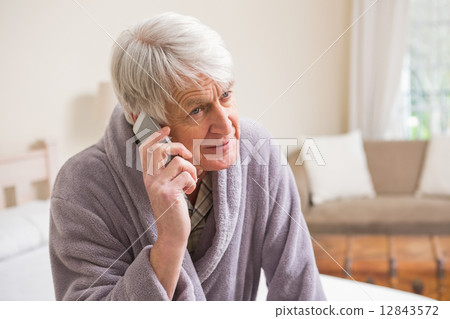 Senior man making a phone call on bed 12843572
