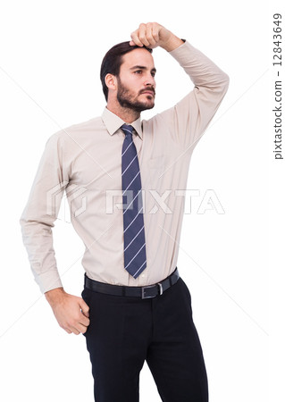 Serious businessman standing with hand on head 12843649