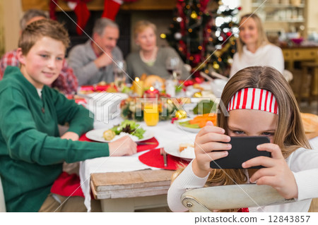 Little girl holding smartphone during christmas dinner Little girl holding smartphone during christmas dinner 12843857