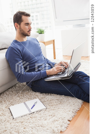 Young man sitting on floor using laptop Young man sitting on floor using laptop 12843859