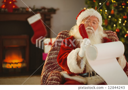 Concentrated santa writing his list on a scroll 12844243