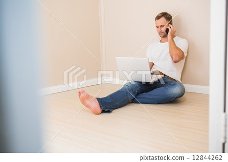 Man using laptop and talking on phone Man using laptop and talking on phone 12844262